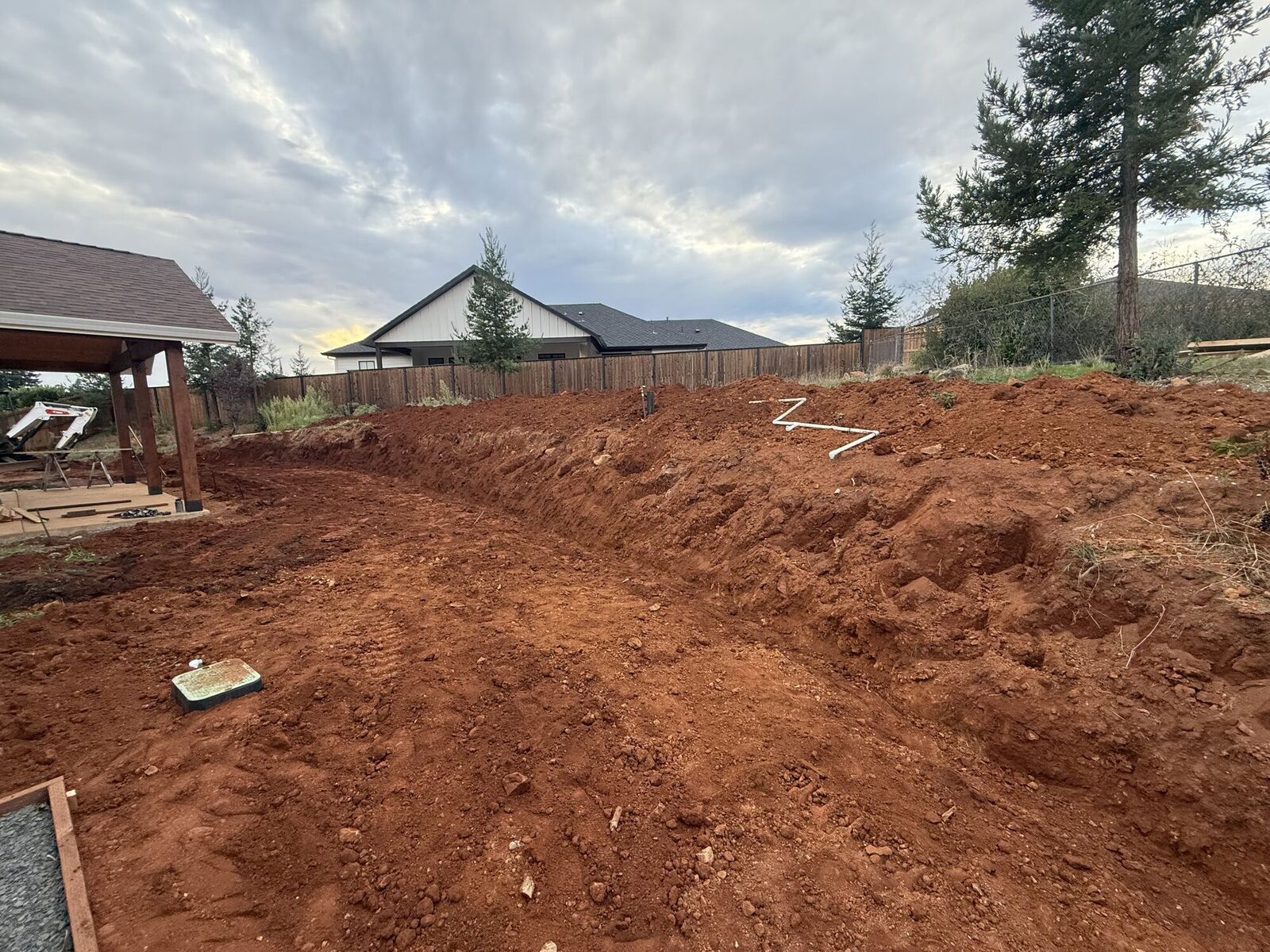 Backyard red-soil excavation and grading before retaining wall