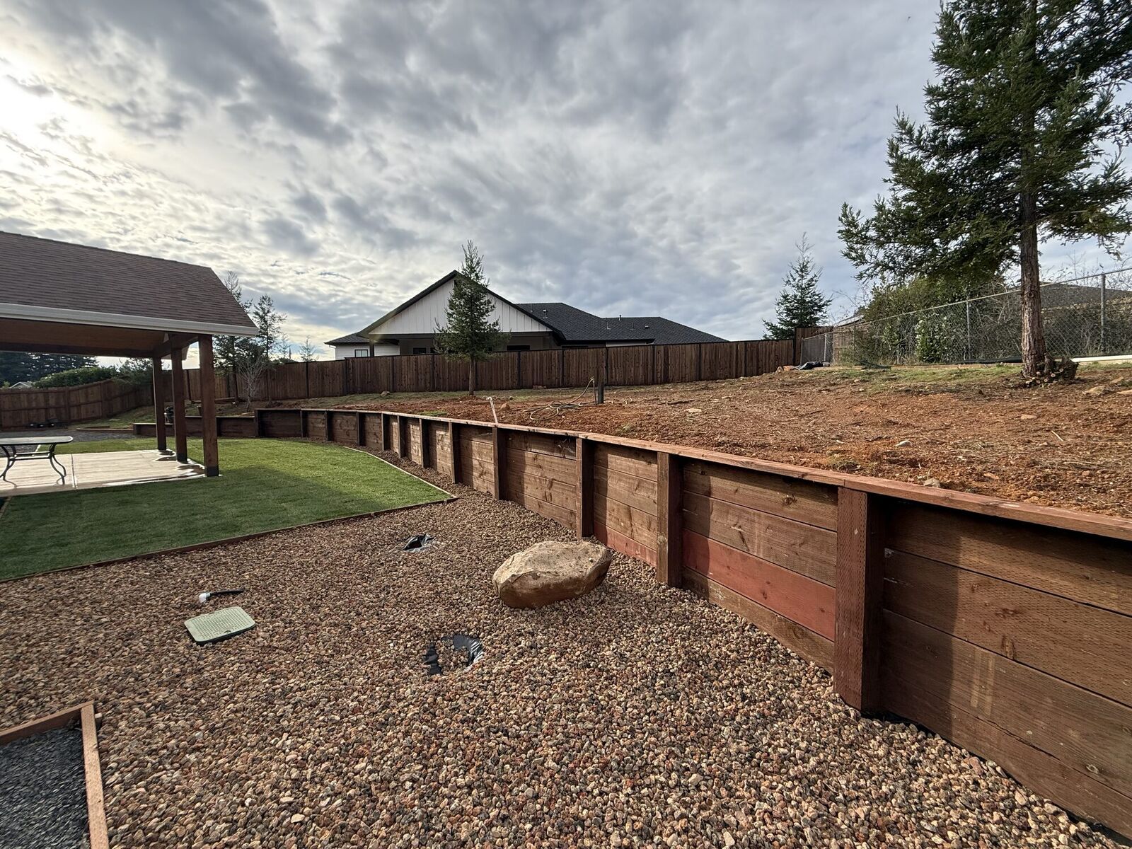 Finished terraced wood retaining wall with rock and lawn